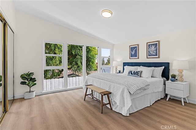 bedroom with light hardwood / wood-style flooring, a closet, and vaulted ceiling