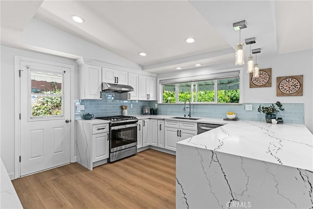 kitchen with hanging light fixtures, appliances with stainless steel finishes, sink, white cabinetry, and light stone counters