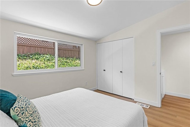 bedroom featuring a closet, vaulted ceiling, and light hardwood / wood-style flooring