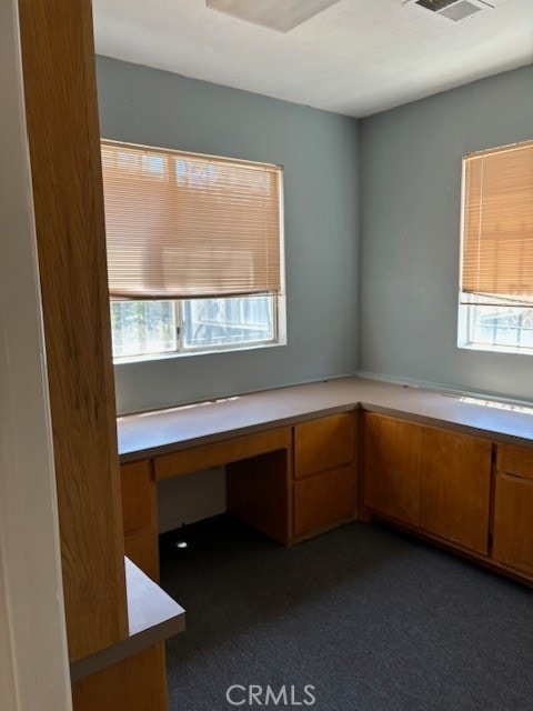 unfurnished office with built in desk and dark colored carpet