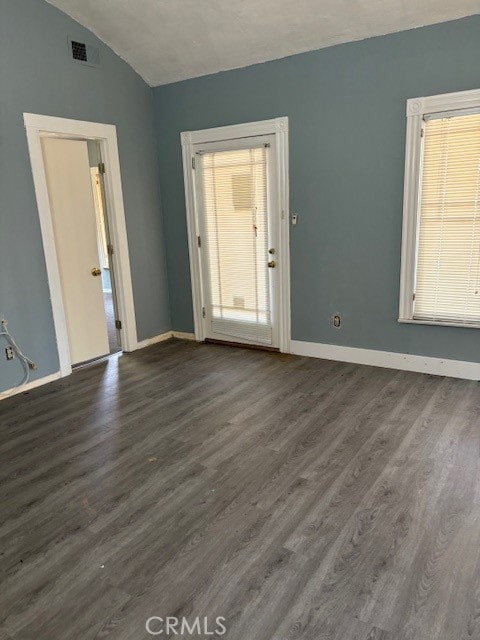 unfurnished room featuring a healthy amount of sunlight, lofted ceiling, and dark hardwood / wood-style floors