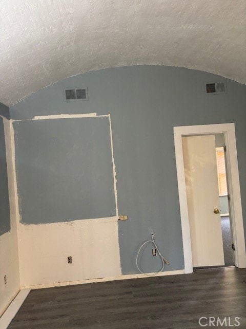 unfurnished room featuring a textured ceiling, lofted ceiling, and dark hardwood / wood-style floors