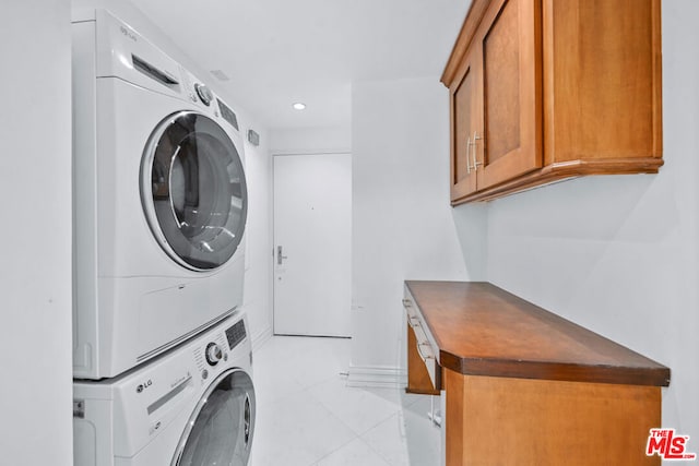 washroom with cabinets, stacked washer and clothes dryer, and light tile patterned floors