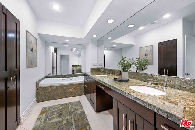 bathroom featuring vanity, a relaxing tiled tub, and tile patterned floors