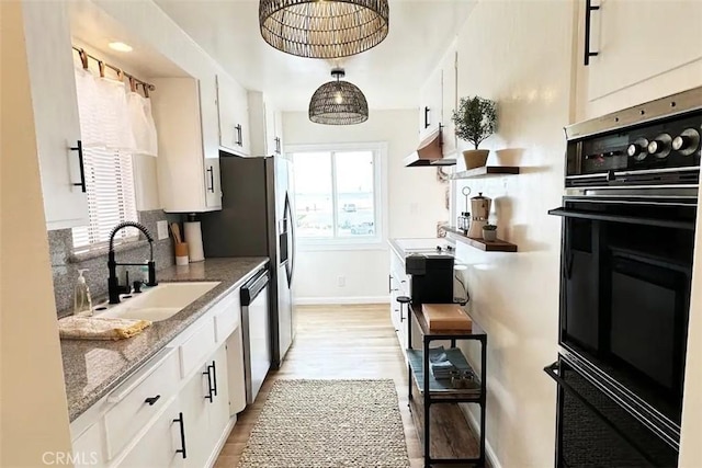 kitchen with white cabinetry, light stone countertops, black oven, and stainless steel dishwasher