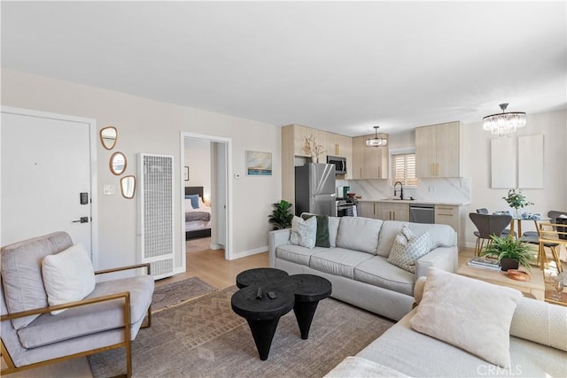 living room featuring sink, light wood-type flooring, and an inviting chandelier