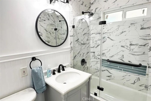 full bathroom featuring vanity, shower / bath combination with glass door, and toilet