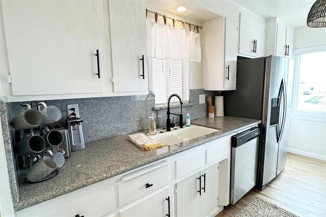 kitchen with sink, stainless steel dishwasher, white cabinets, and decorative backsplash