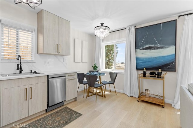 kitchen featuring dishwasher, sink, a chandelier, light brown cabinets, and light wood-type flooring