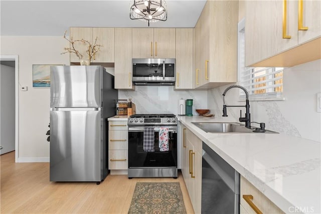 kitchen featuring appliances with stainless steel finishes, sink, backsplash, light stone counters, and light brown cabinets