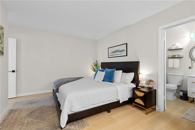 bedroom with connected bathroom and light hardwood / wood-style floors