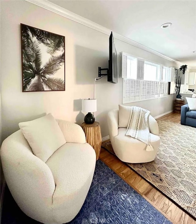 sitting room with hardwood / wood-style floors and ornamental molding