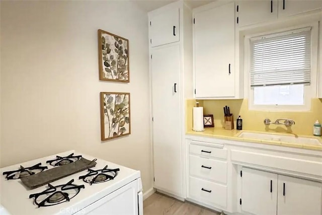 kitchen with a wealth of natural light, sink, white cabinetry, and white range with gas cooktop