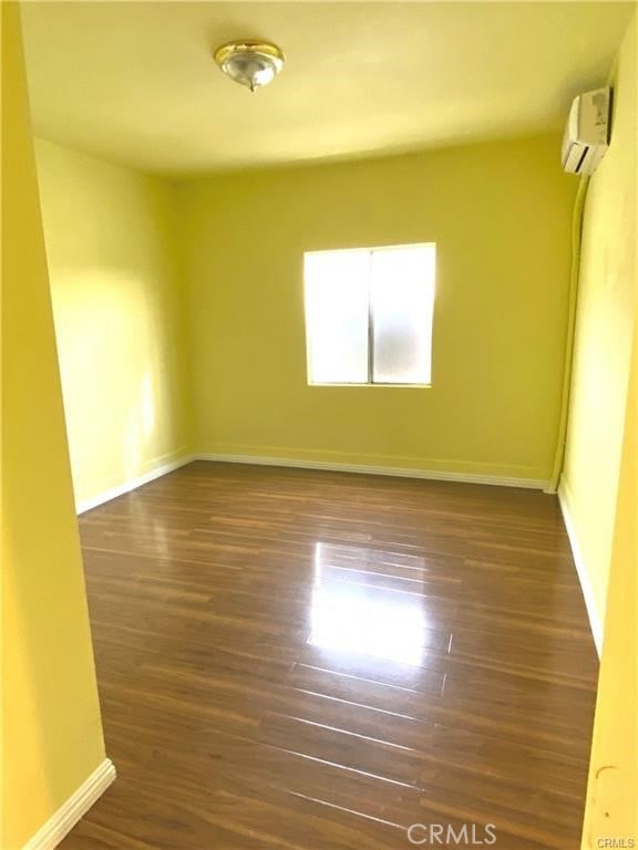 empty room featuring dark hardwood / wood-style floors and a wall mounted AC