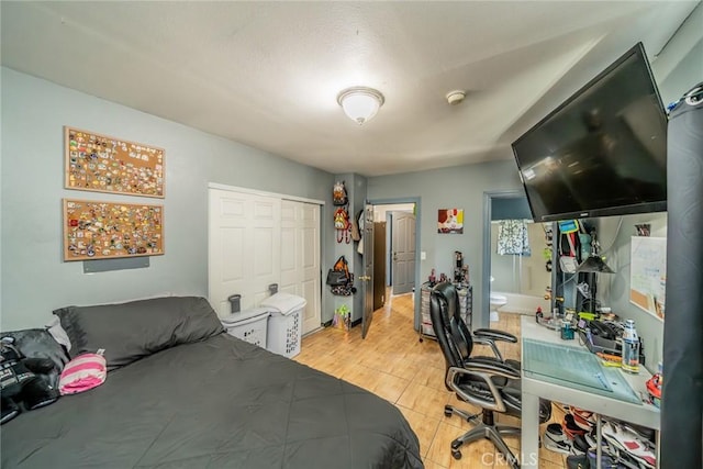 bedroom featuring connected bathroom, a closet, and light wood-type flooring