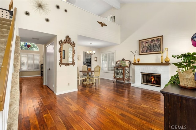 unfurnished living room with beam ceiling, a fireplace, high vaulted ceiling, an inviting chandelier, and hardwood / wood-style floors