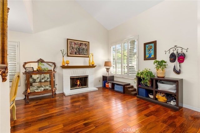 sitting room with a fireplace, dark wood-type flooring, and high vaulted ceiling