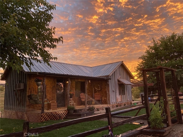 view of front of house with a porch, metal roof, and fence