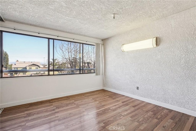 spare room featuring hardwood / wood-style flooring and a textured ceiling