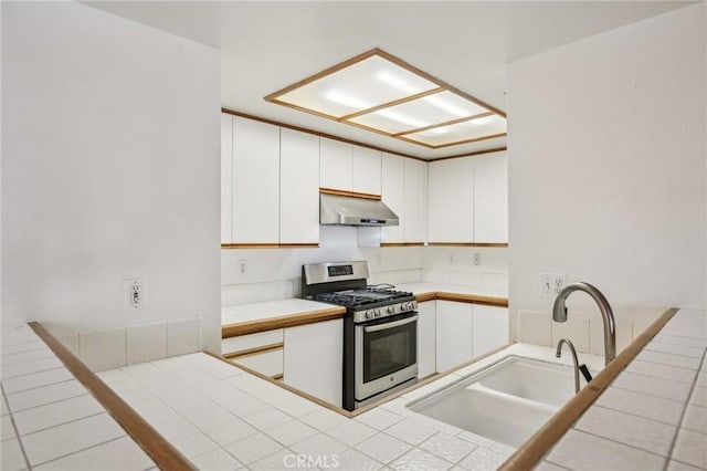 kitchen with white cabinetry, stainless steel range with gas cooktop, tile counters, and sink