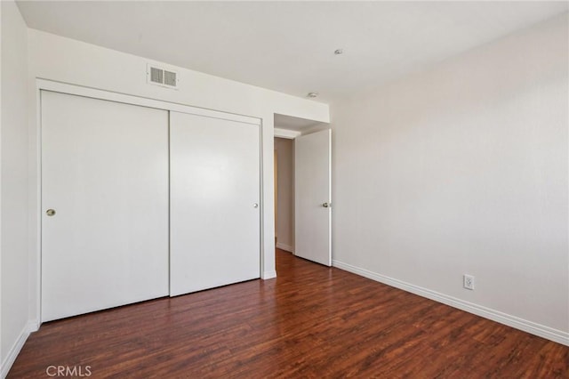 unfurnished bedroom featuring dark hardwood / wood-style flooring and a closet