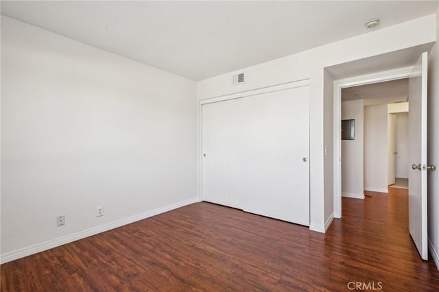 unfurnished bedroom with dark wood-type flooring and a closet