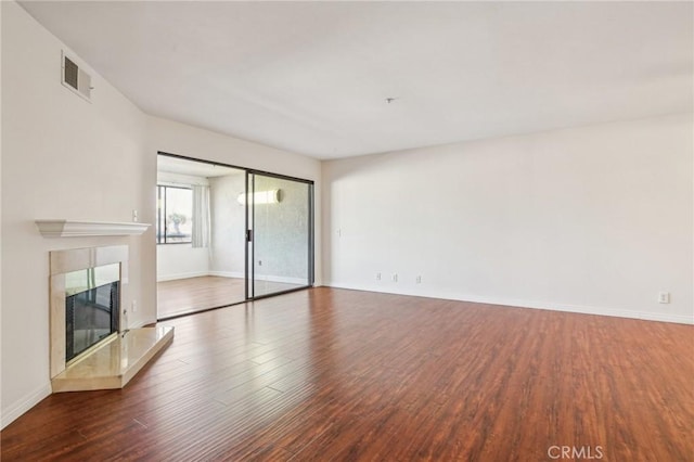 unfurnished living room with a tiled fireplace and hardwood / wood-style flooring