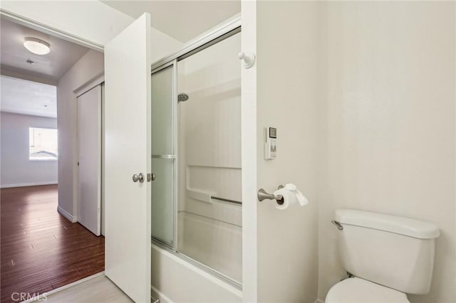 bathroom with enclosed tub / shower combo, toilet, and hardwood / wood-style floors