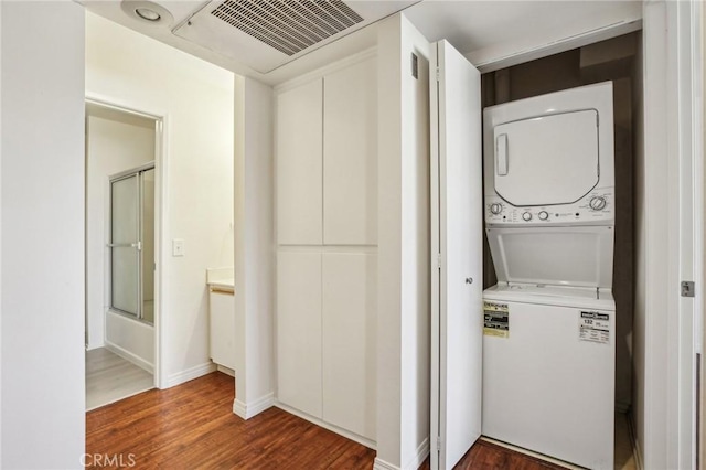 washroom with hardwood / wood-style flooring and stacked washing maching and dryer