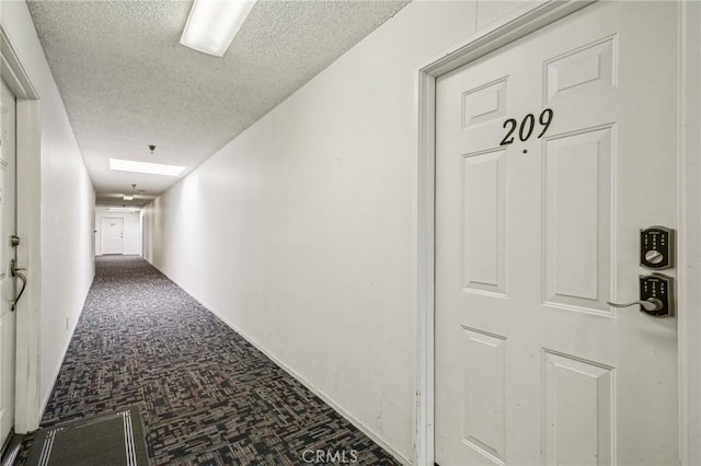 corridor with carpet flooring and a textured ceiling