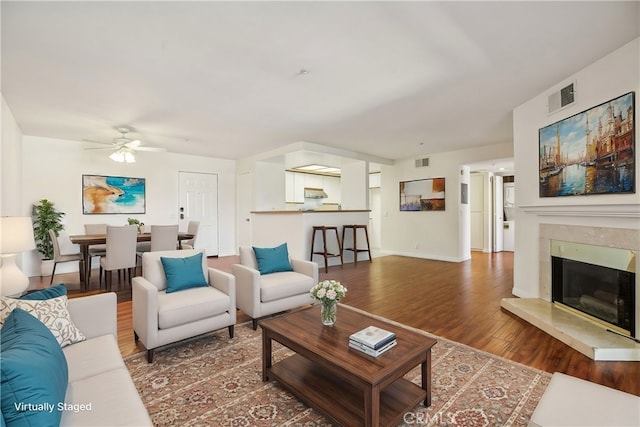 living room featuring ceiling fan, a high end fireplace, and dark hardwood / wood-style floors