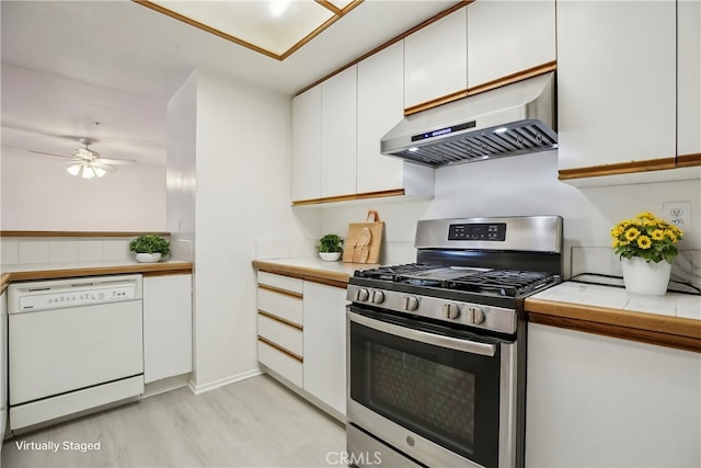 kitchen featuring light hardwood / wood-style flooring, white cabinetry, white dishwasher, stainless steel gas range oven, and ventilation hood