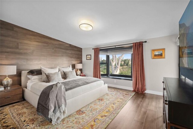 bedroom featuring hardwood / wood-style floors, lofted ceiling, and wood walls