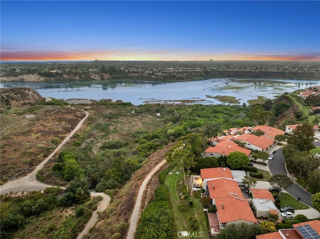 aerial view at dusk featuring a water view