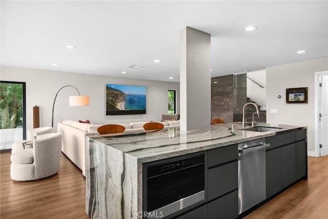 kitchen featuring a wealth of natural light, a kitchen island with sink, dishwasher, and dark hardwood / wood-style flooring