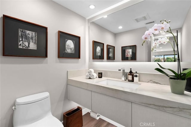 bathroom with toilet, vanity, and hardwood / wood-style flooring