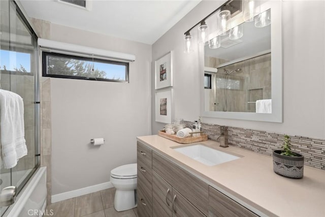 full bathroom with backsplash, tile patterned floors, bath / shower combo with glass door, toilet, and vanity