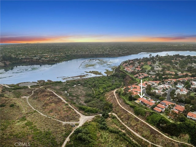 aerial view at dusk featuring a water view