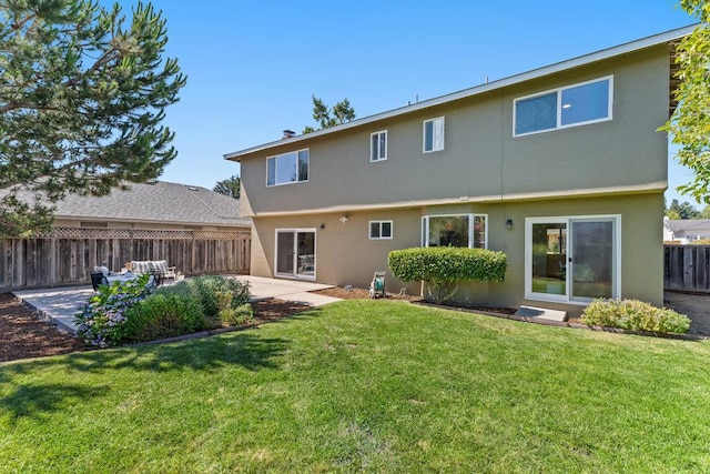 back of house with a lawn and a patio