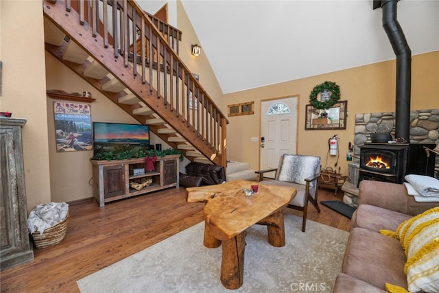 living room with wood-type flooring, a wood stove, and high vaulted ceiling