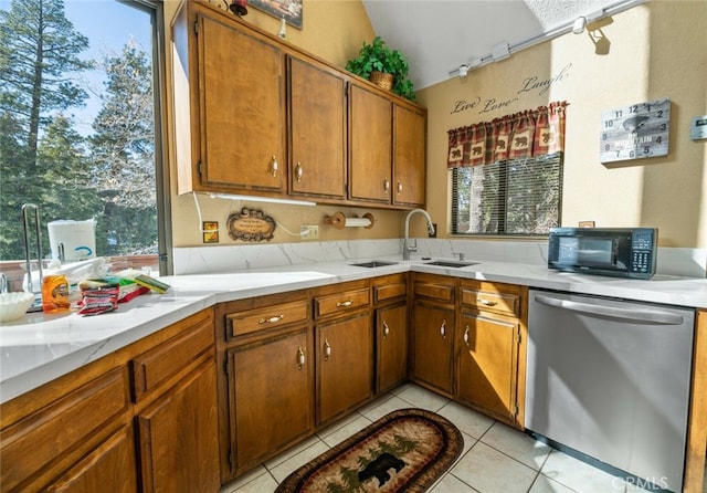 kitchen with vaulted ceiling, sink, light tile patterned floors, and stainless steel dishwasher