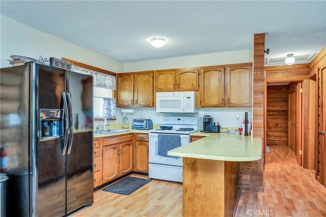 kitchen featuring light hardwood / wood-style flooring, kitchen peninsula, a textured ceiling, and white appliances