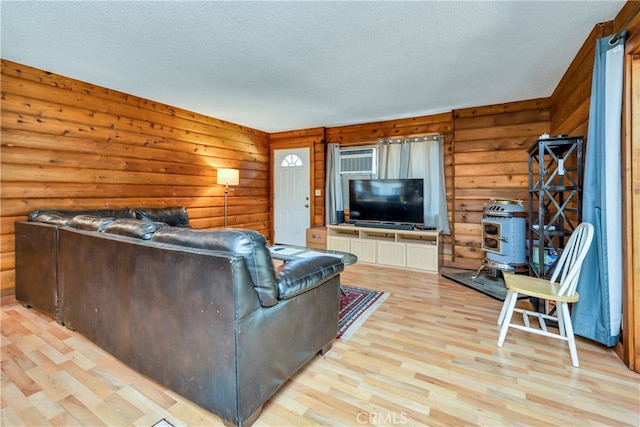 living room featuring a textured ceiling, an AC wall unit, log walls, and light wood-type flooring