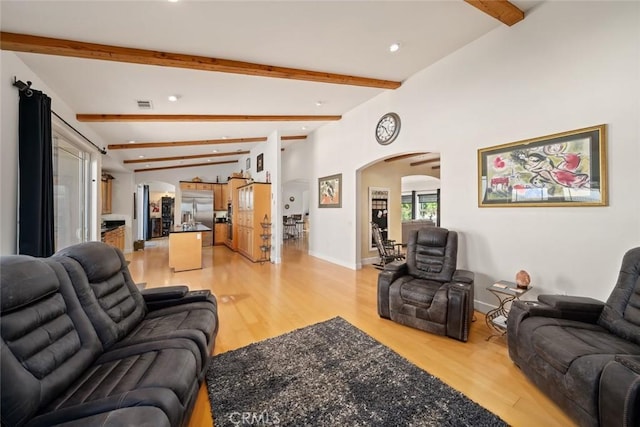 living area with arched walkways, light wood-style flooring, visible vents, and baseboards