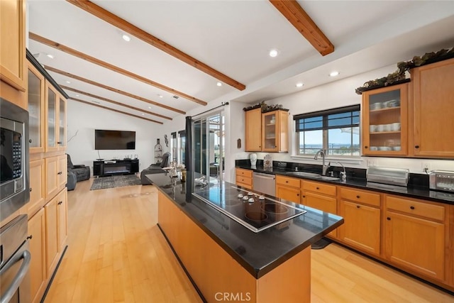 kitchen featuring light wood finished floors, an island with sink, vaulted ceiling with beams, stainless steel appliances, and a sink