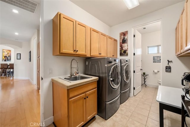 clothes washing area featuring arched walkways, a sink, visible vents, baseboards, and washing machine and clothes dryer