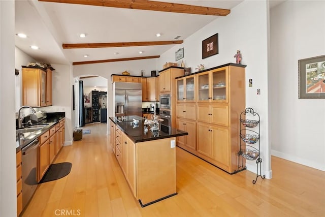 kitchen with arched walkways, a sink, dark countertops, and built in appliances