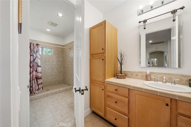 full bathroom featuring tile patterned flooring, tiled shower, and vanity