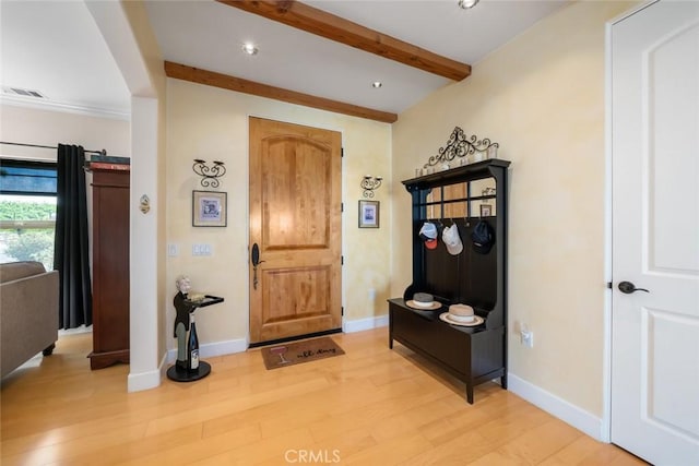 foyer entrance with light wood-type flooring, beam ceiling, visible vents, and baseboards