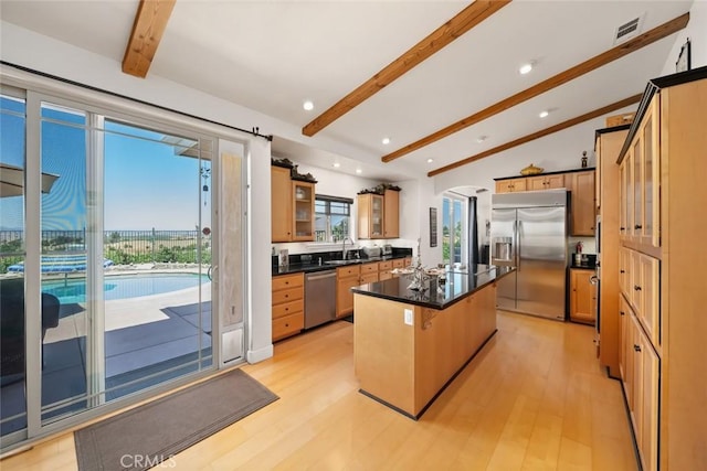 kitchen with visible vents, appliances with stainless steel finishes, light wood-type flooring, a center island, and dark countertops